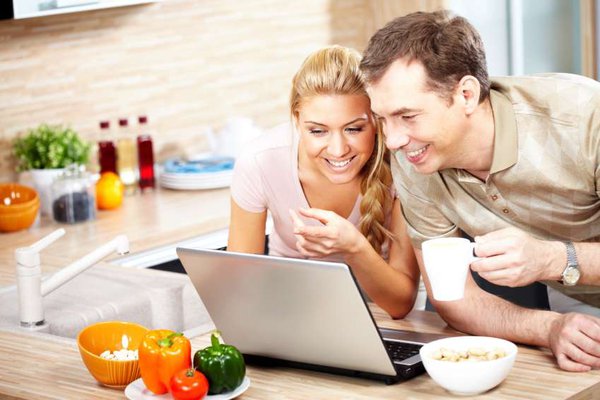 A couple looks at a computer screen.