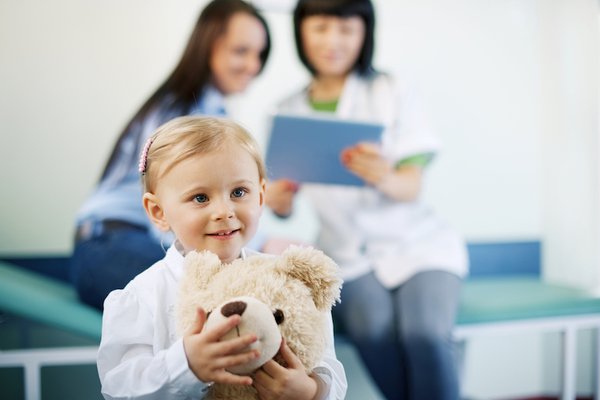 A child sits and holds a stuffed bear.