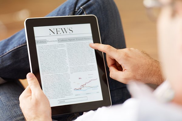 Man pointing at the news on his tablet