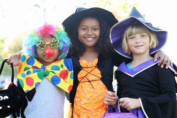 Children smile while wearing Halloween costumes.