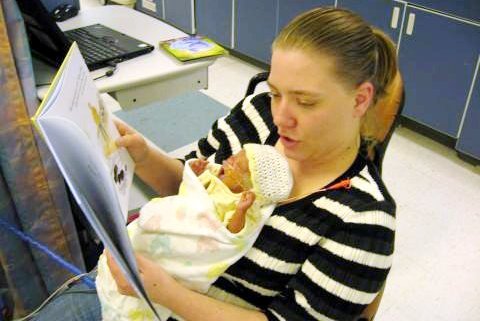 Mom reads to a newborn baby.