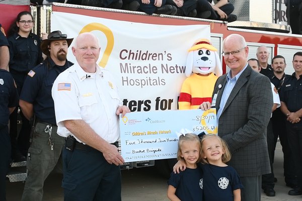 Marshfield Fire Department officers present a check to CMH Hospitals at CoxHealth