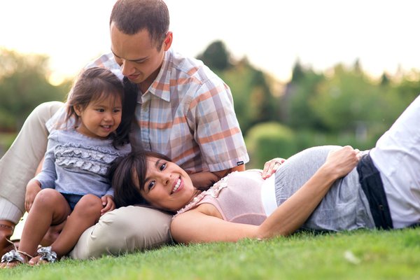 Family of three sit in the grass