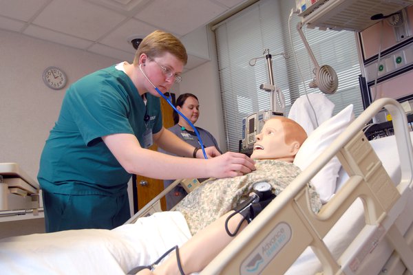 A Cox College trains with a simulation mannequin.