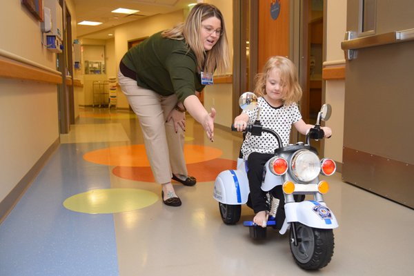 Child Life encourages play while in the hospital, including by riding a trike down the hallways.