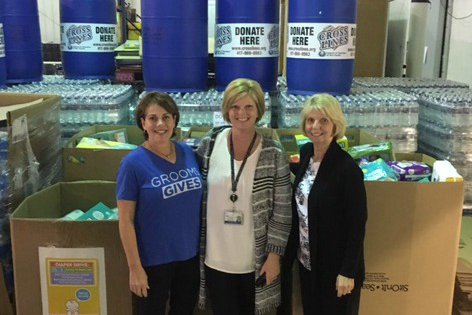 Three woman standing in front of donations.