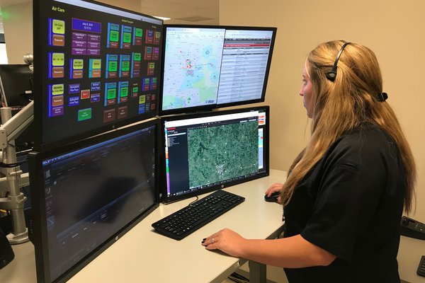 A dispatcher stands at her computer station.