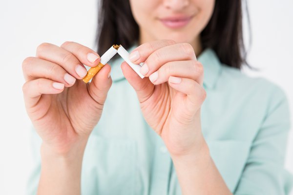 A woman breaks a cigarette in half.