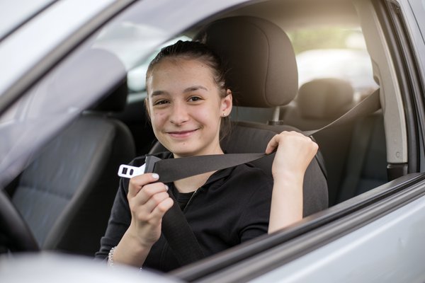 A young adult sits in a car.