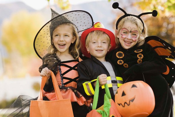 Three kids dressed up for Halloween as a witch, fire fighter, and butterfly