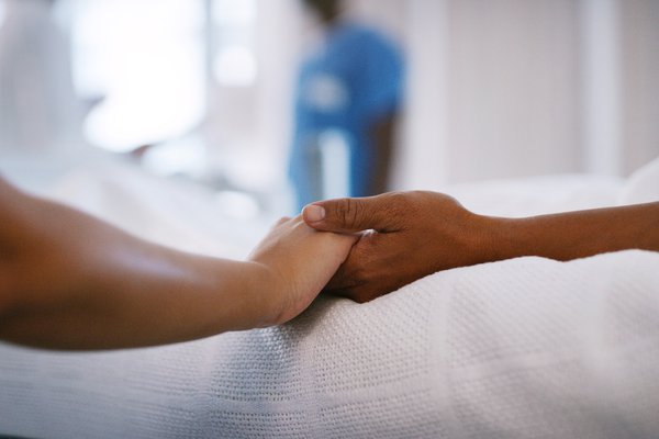 A caregiver holds hands with a patient.