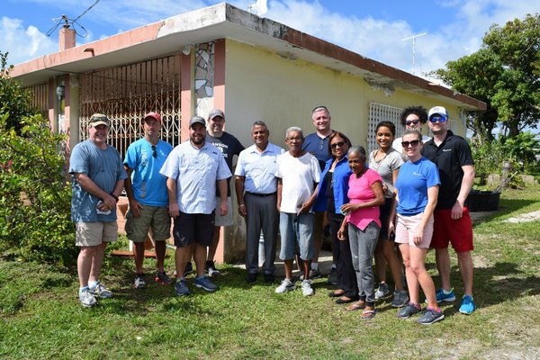 A group of leaders pose with Virginia, whose home is being renovated.