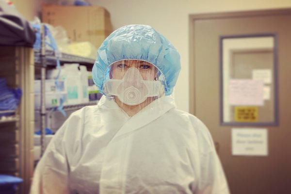 A nurse stands in PPE.