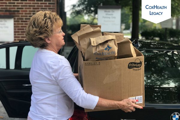 A woman prepares to put Meals on Wheels deliveries in her car.