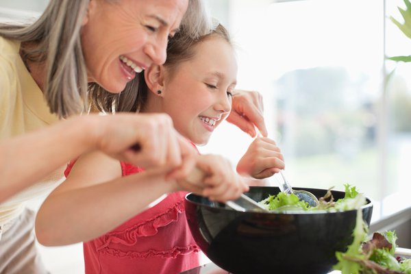 Grandma helping granddaughter make a salad