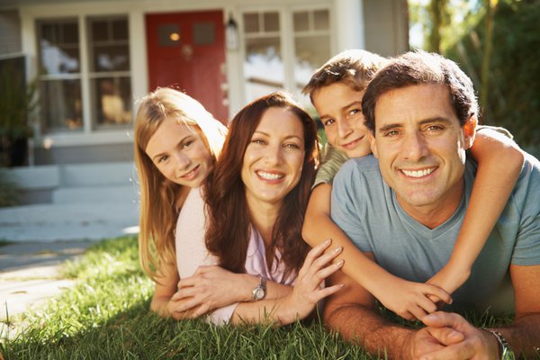 A family sits in front of a house.