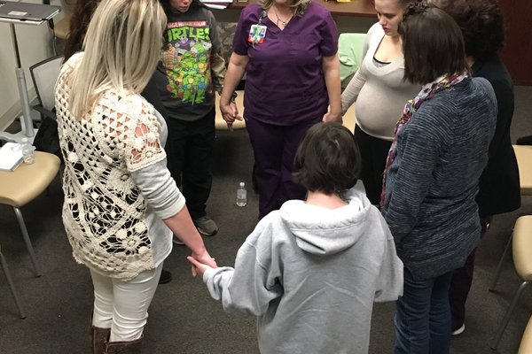 Group of women in a circle holding hands.