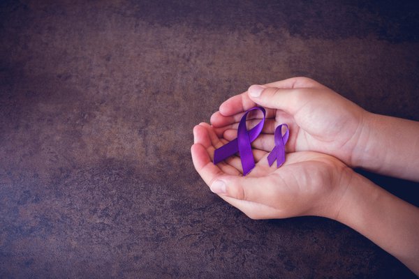 Hands hold purple ribbons.