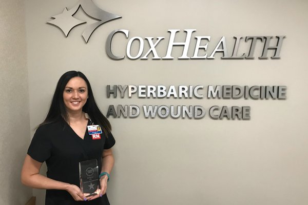 Samantha Wooldridge stands near a CoxHealth sign with her award.