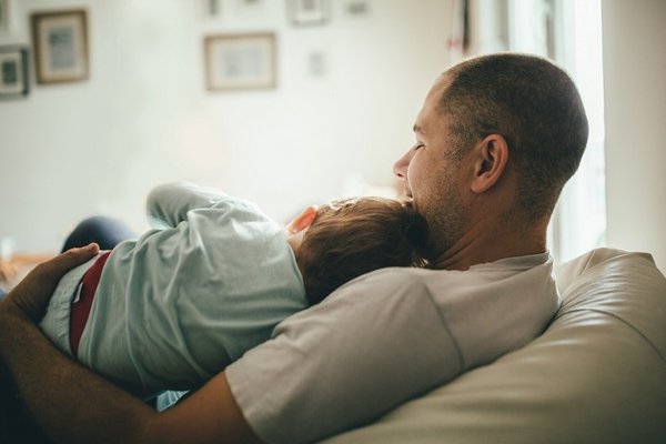 A father and child recline at home.