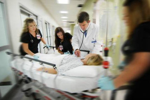 A stroke patient is wheeled down a hallway.