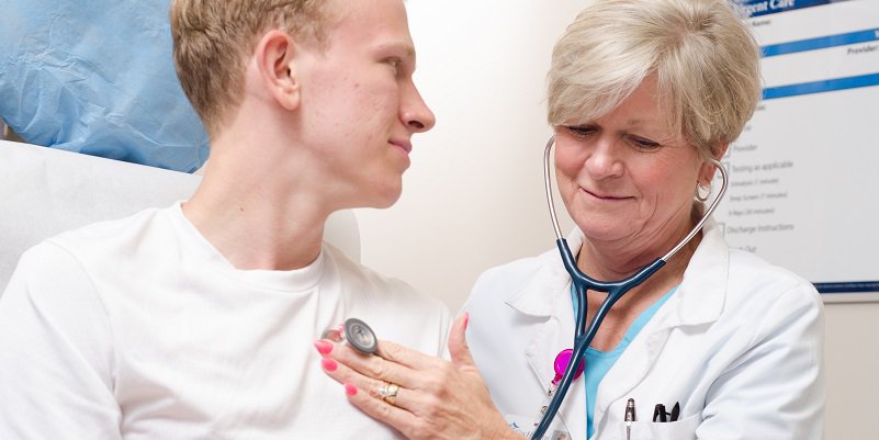 An urgent care doctor listens to her patient's heart.