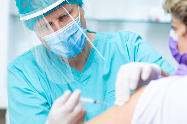 An image shows an individual receiving a vaccine.