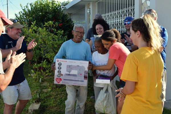 A group stands with Virginia after she receives her sewing machine.