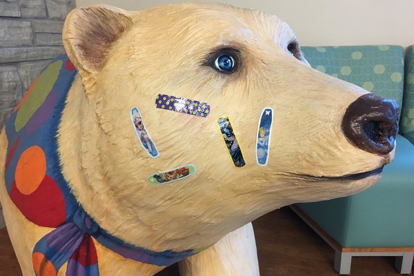 Bear statue with bandaids on it.