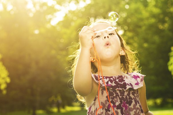 A little girl blows bubbles.