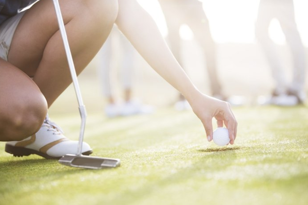 A golfer sets a golf ball in place.