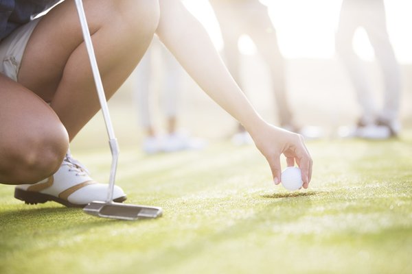 Man getting his golf ball off the grass