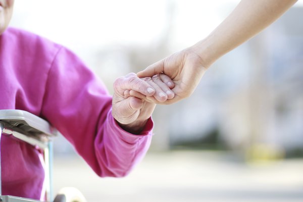 A caregiver holds hands with a patient.