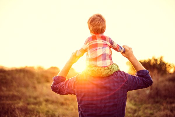 A man holds a child on his shoulders.