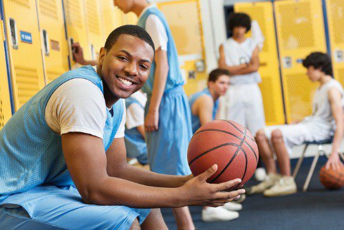 A basketball player smiles at the camera.